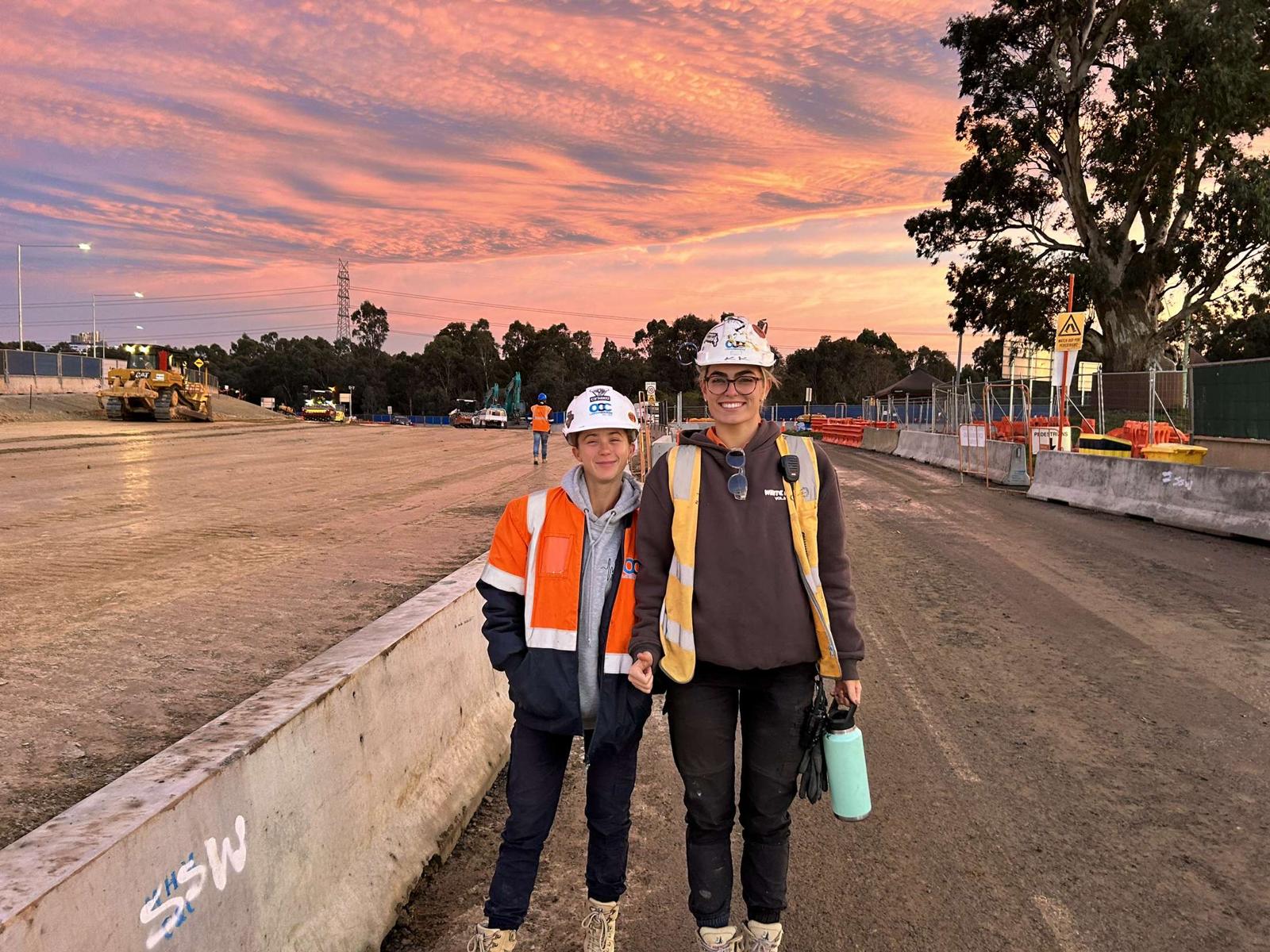 Two construction workers on site at sunset